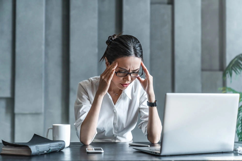 Young woman working on laptop having headache