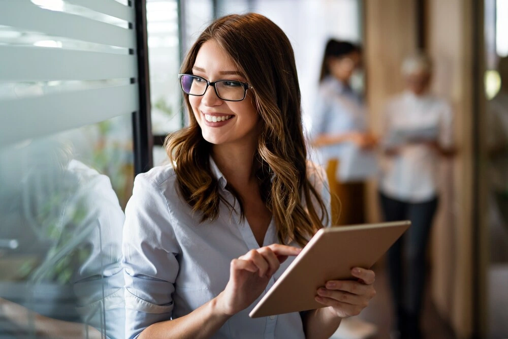 Young happy business woman working with tablet in corporate office